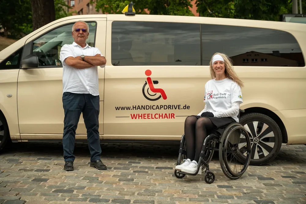 Fahrer und Kundin vor dem Rollstuhltaxi von Handicap Drive